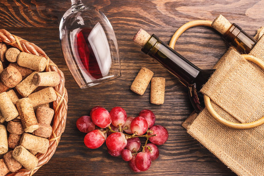 Glass with wine, bottles and bunch of grapes, wooden background