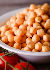 White bowl full of yellow wet chickpeas and tomatoes