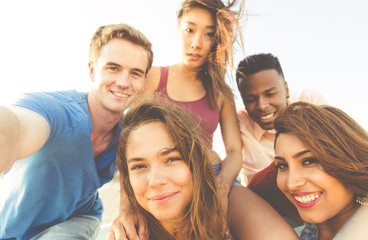 Mixed race group of friends walking in Santa monica beach and taking selfie