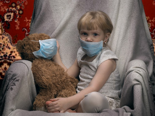Small child with a toy bear cub in a medical mask. Carpet, rug. Concept - an allergy to dust, wool, asthma. Carpet harm. © kozorog