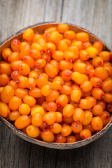 Buckthorn berry basket on wooden background.