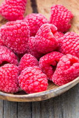 Frozen raspberries on wooden background.
