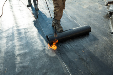 Installation of roll roofing waterproofing propane blowtorch during construction - obrazy, fototapety, plakaty