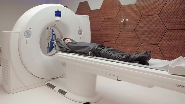 Young Caucasian male gets scanned by magnetic resonance imaging scanner in modern hospital