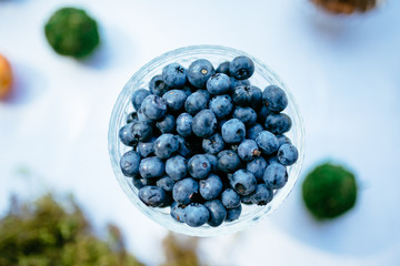 A few blueberries in glass vase on white background