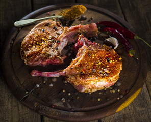 raw pork steak on a wooden surface with spices