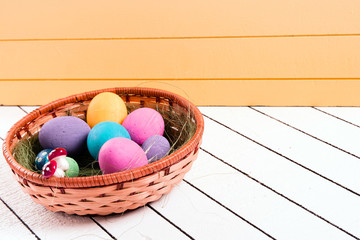 Colorful Easter eggs in basket on a wooden background. Eco-friendly material without violence against animals