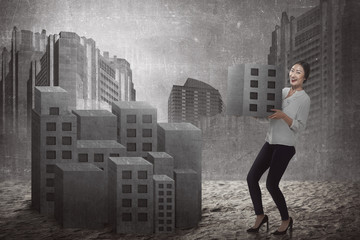 Asian business woman lifting block of city
