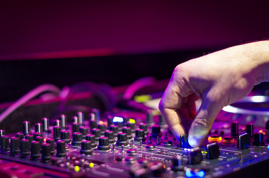 Dj mixes the track in the nightclub at party - music and technology concept
