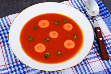 Carrot Tomato Soup in Plate. Behind lie on the soup ingredients,
