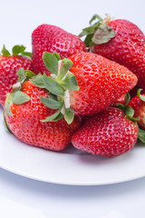 Strawberry red on a white plate and a white background, a bright image with contrast. side view, top. summer red berries. a series of color photographs