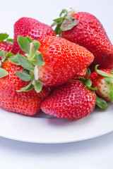Strawberry red on a white plate and a white background, a bright image with contrast. side view, top. summer red berries. a series of color photographs