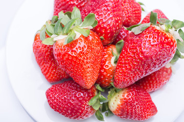 Strawberry red on a white plate and a white background, a bright image with contrast. side view, top. summer red berries. a series of color photographs