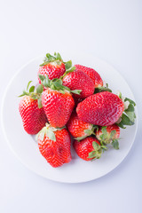 Strawberry red on a white plate and a white background, a bright image with contrast. side view, top. summer red berries. a series of color photographs
