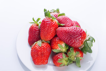 Strawberry red on a white plate and a white background, a bright image with contrast. side view, top. summer red berries. a series of color photographs