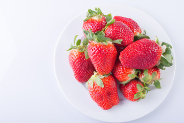 Strawberry red on a white plate and a white background, a bright image with contrast. side view, top. summer red berries.