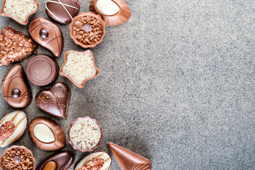 Assorted delicious chocolate pralines background on grey texture, place for text, product...