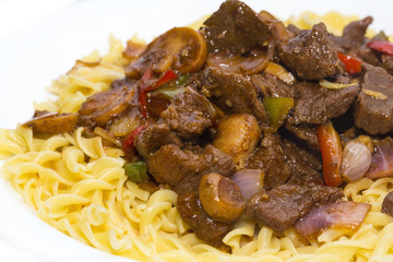 pasta with pork and mushrooms on a white plate in a restaurant