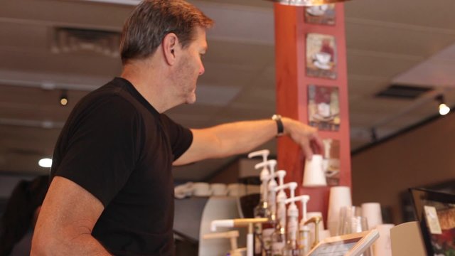 A coffee shop owner waits on customers