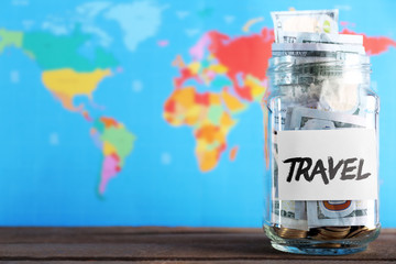 Fototapeta na wymiar Savings for trip in glass bank on colourful map background