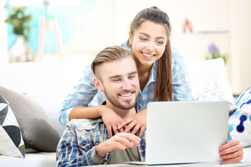 Happy couple sitting at the table and working with a laptop