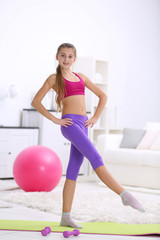 Fototapeta na wymiar Young girl making fitness exercise indoors