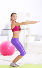 Fototapeta na wymiar Young girl making fitness exercise indoors
