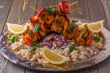 Grilled chicken and vegetable kebabs served with rice and salad.