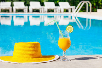 Obraz premium Bright hat with cocktail over a swimming pool, vacations concept