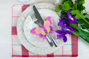 Obraz na płótnie Canvas crockery and Cutlery on a napkin next to green chrysanthemum with other flowers on wooden white table