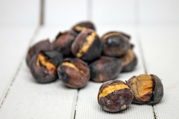 hot toasted chestnuts on white wooden background