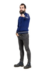 Confident serious hipster in blue tracksuit jacket pointing finger at camera. Full body length...