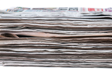 View of a pile of newspapers stacked isolated on a white background.