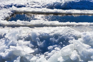 Fototapeta na wymiar broken ice blocks and ice-hole in frozen rive