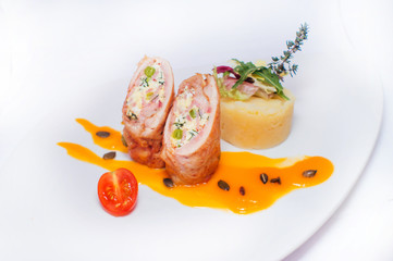 Meatloaf with scrambled eggs garnished with mashed potatoes served on a white plate on a white background