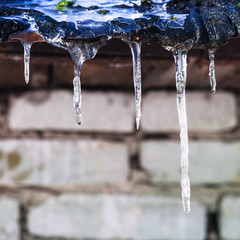 Obraz na płótnie Canvas icicles on roof of barn with brick wall
