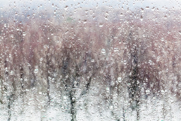 water drops from melting snow on home window glass