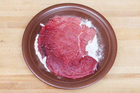 Raw Veal Schnitzel Breaded In Flour On Plate