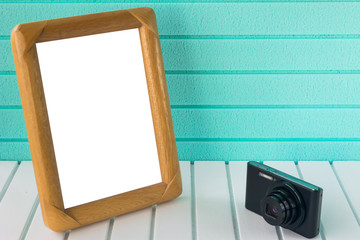 Amateur photo camera and picture frame on white base and light green background