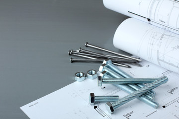 bolts of different shapes and drawings with nails and nuts on wooden brown table