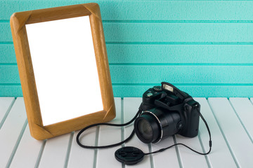 Amateur photo camera and picture frame on white base and light green background