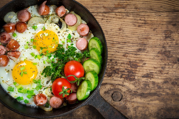 fried eggs with sausages in pan