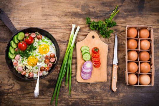 Morning cooking with fried eggs, sausages and vegetables
