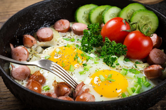 fried eggs with sausages in pan