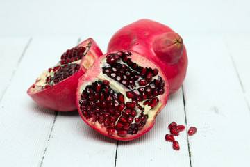 Fresh pomegranate fruits isolated on a white wooden background.