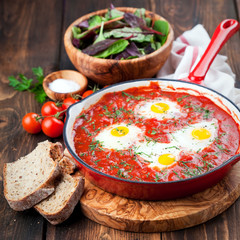 Shakshuka with tomatoes and eggs in a cast iron pan, selective focus