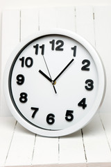 White kitchen clock with black numbers on a white background.