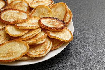 Plate of homemade pancakes on dark table.