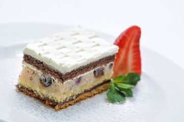 Coconut cake with marzipan and strawberry on white plate, photography for shop, patisserie
