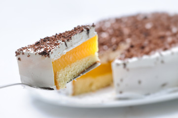 sponge cake with cream and yellow gelatin on metal spoon, tart on white plate, patisserie, photography for shop, birthday cake